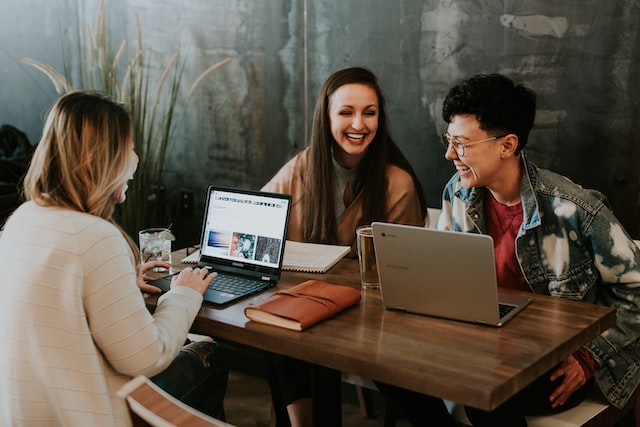 A group of employees sat at a table on their laptops