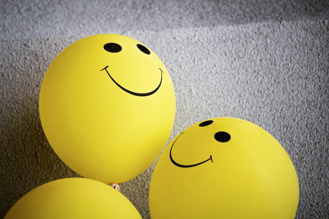 Three yellow balloons with a smiley face imprinted on them for workplace wellbeing